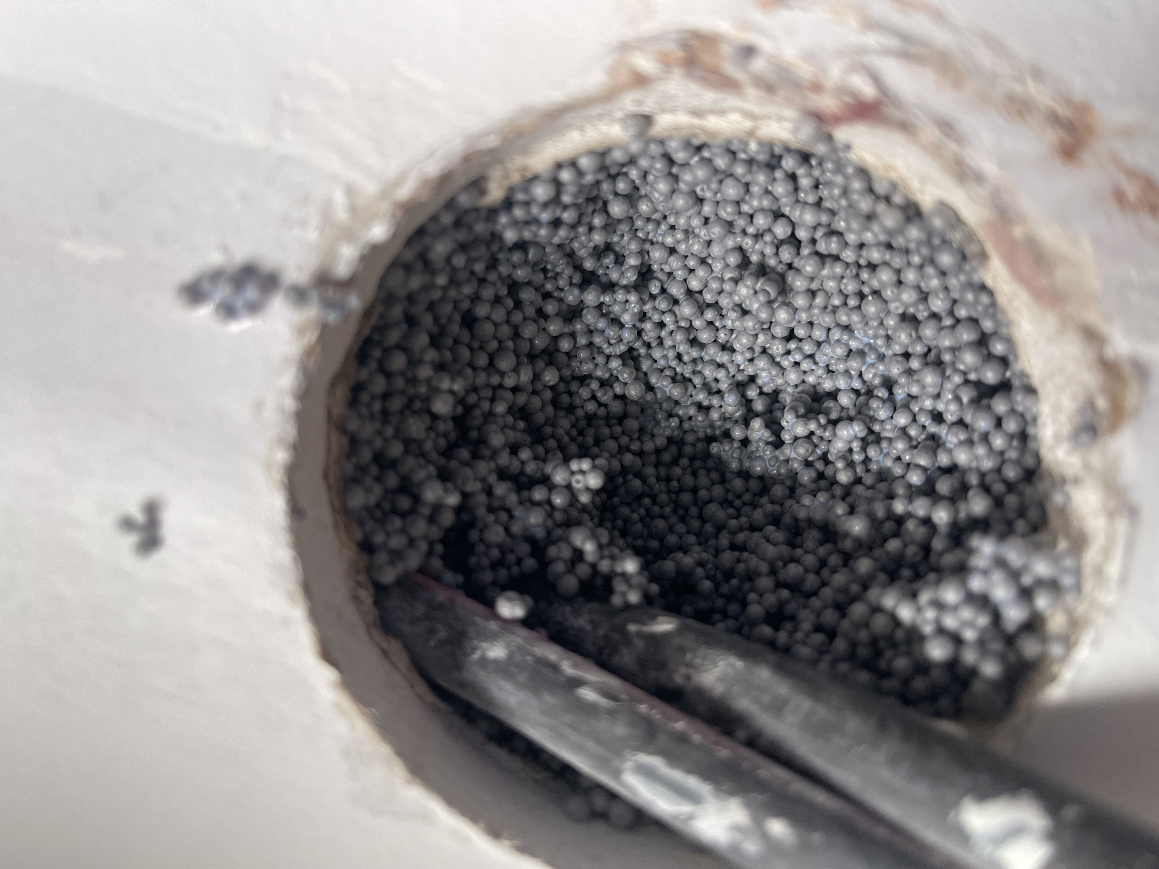 Gros plan sur l'injection de billes de polystyrène dans un mur creux.